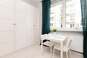 ein weißes Esszimmer mit einem weißen Tisch und Stühlen in der Unterkunft Apartments Gdynia Abrahama in Gdynia