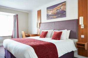 a hotel room with a large bed with red pillows at Wheatsheaf by Chef & Brewer Collection in North Waltham