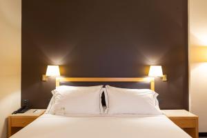 een slaapkamer met een groot wit bed met 2 lampen bij City Life Hotel Poliziano, by R Collection Hotels in Milaan