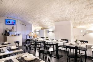 パリにあるオテル ド ラ ガイテの白いテーブルと黒い椅子が備わるレストラン
