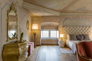 ein Schlafzimmer mit einem Bett, einem Spiegel und einer Kommode in der Unterkunft Rooms Castelvecchio - Palazzo Canossa in Verona