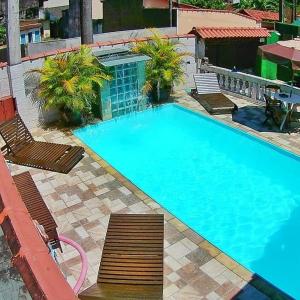 a large swimming pool with two chairs at Toca do Capitao in Boicucanga