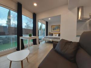 a living room with a couch and a table and a bed at Acero y Piedra Apartamentos con jardín privado in Cerceda