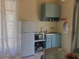 a kitchen with a white refrigerator and blue cabinets at Kefalonia apartments - Marias studios in Spartia in Spartia