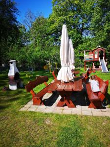a picnic table with a white umbrella and chairs at Szkolne Schronisko Młodzieżowe PLUM in Piechowice