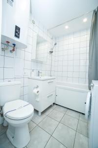 e bagno bianco con servizi igienici, lavandino e vasca. di TF Apartment двокімнатні апартаменти в центрі міста a Poltava