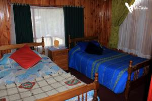 a bedroom with two twin beds and a window at Hospedaje Isla Talcan in Dalcahue