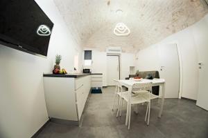 una cucina con mobili bianchi, tavolo e sedie di Elaion Home a Ostuni