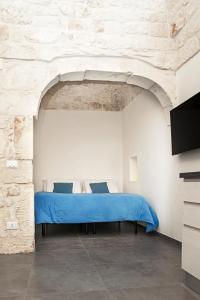 um quarto com uma cama azul numa parede de pedra em Elaion Home em Ostuni