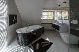a bathroom with a black and white tub and a sink at ApartView na Mazurach "Osada Zamkowa" by Rent like home in Pasym