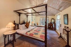 a bedroom with a canopy bed and a table with a lamp at SaffronStays Parsi Manor, Matheran in Matheran