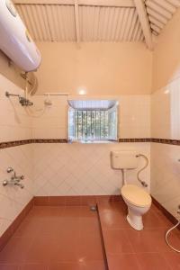 a bathroom with a toilet and a shower and a window at SaffronStays Parsi Manor, Matheran in Matheran
