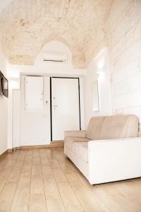 een woonkamer met een witte bank en een houten vloer bij Liberty Bell in Ostuni