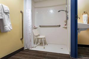 a bathroom with a shower and a sink and a chair at Days Inn by Wyndham Augusta in Augusta