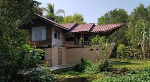 a wooden house with a porch and a balcony at Big Hug Home in Ko Yao Noi