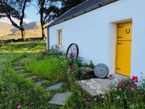 un edificio bianco con una porta gialla e alcuni fiori di Thistle Thatch Cottage and Hot Tub - Mourne Mountains a Newcastle Altre 14 foto