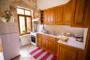 uma cozinha com armários de madeira e um frigorífico branco em Picturesque Traditional Stone House em Plátanos