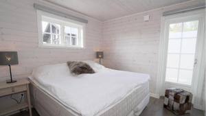 ein Bett in einem weißen Zimmer mit einer Katze, die darauf schläft. in der Unterkunft Jarvso House. Ski In / Ski Out. in Järvsö