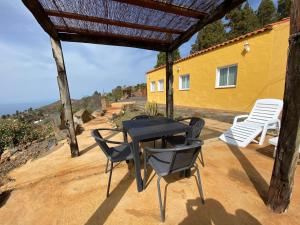 een patio met een tafel en stoelen en een huis bij Breñoso 2 in Puntagorda