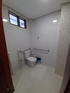 a white bathroom with a toilet and a window at Hotel Asa Branca in Belo Jardim