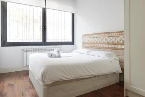 サン・セバスティアンにあるEider - Basque Stayのベッドルーム1室(大型ベッド1台、白いシーツ、窓2つ付)
