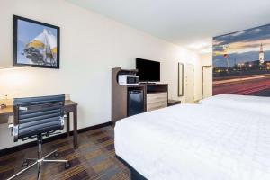 Habitación de hotel con cama, escritorio y TV. en Clarion Pointe Madison-Huntsville, en Madison