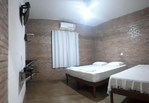 a bedroom with two beds and a brick wall at Pousada Nuporanga in Nuporanga