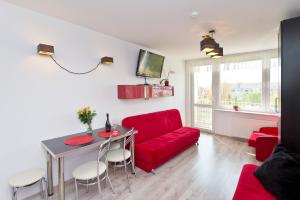 - un salon avec un canapé rouge et une table dans l'établissement Apartament Słoneczne Południe, à Gdańsk