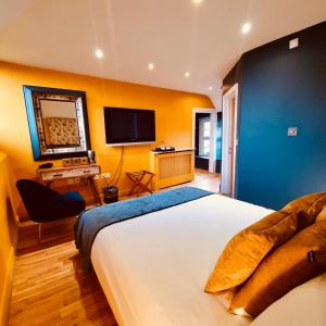 a bedroom with a large bed and a flat screen tv at The Old Lodge in Stroud