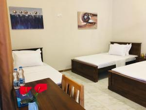 a room with two beds and a table with red flowers at Pearl Nest in Galle