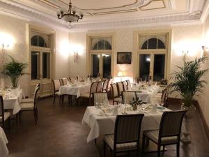 uma sala de jantar com mesas e cadeiras brancas e um lustre em Schlossgut Gorow em Satow
