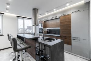 a kitchen with a sink and a counter with stools at InshiApartments on Hazova str 5 in Lviv