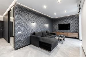 InshiApartments on Hazova str 5 في إلفيف: غرفة معيشة مع أريكة سوداء وتلفزيون