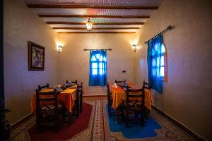 a dining room with tables and chairs with blue curtains at Riad Les jardins de Merzouga in Merzouga