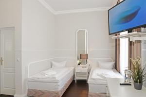 sala de estar con muebles blancos y TV de pantalla plana en Hotel Stralsund, en Stralsund