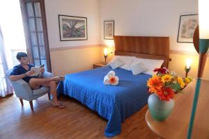 a man sitting in a chair reading a book in a bedroom at Villa Rossana in Cenaia +61 photos