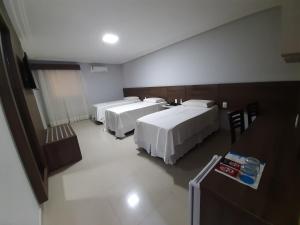 a hotel room with three beds and a table at Hotel Asa Branca in Belo Jardim