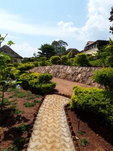 a walkway in a garden with a stone wall at NENA HOUSE in Rusatira