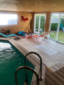 eine Holzterrasse mit einem Pool neben dem Wasser in der Unterkunft Séjour -Chambre d'hôte in Saint-Ours