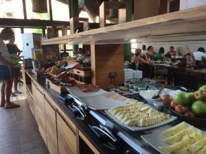 una línea de buffet con queso y otros alimentos en un restaurante en Angra dos Reis Apartamento com Vista para o Mar 6 Condomínio Porto Bali Complexo Mercure, en Angra dos Reis