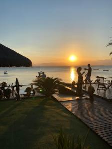 un grupo de personas de pie cerca del océano al atardecer en Pôr do Sol Ilha do Mel Pousada e Receptivo, en Ilha do Mel