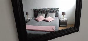 a reflection of a bed with pink pillows in a mirror at Jolie T2 au coeur du bourg in Carnac