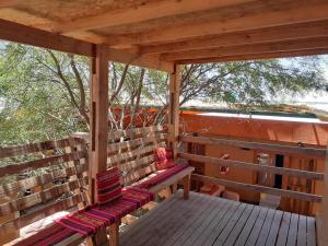 porche de madera con banco en la cubierta en Hostal Nuevo Amanecer, en San Pedro de Atacama