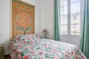 a bedroom with a bed with a colorful bedspread and a window at La Terrasse des Remparts - Welkeys in Antibes