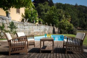 un grupo de sillas y una mesa junto a una piscina en Paço de S.Cipriano, en Guimarães