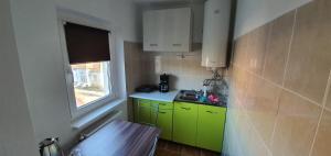 a small kitchen with green cabinets and a window at Garsoniera Horezu in Horezu