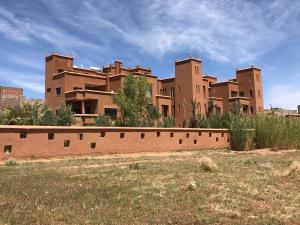 a large building with a brick wall in a field at Kasbah Tamsna in Ouarzazate