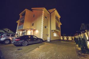 dos autos estacionados frente a un edificio por la noche en Vila Darimar Chișoda, en Chişoda