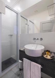 a white bathroom with a sink and a shower at Casa do Campo de São Francisco in Ponta Delgada