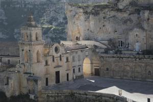 an old building with a tower in front of a mountain at La Corte Dei Pastori in Matera